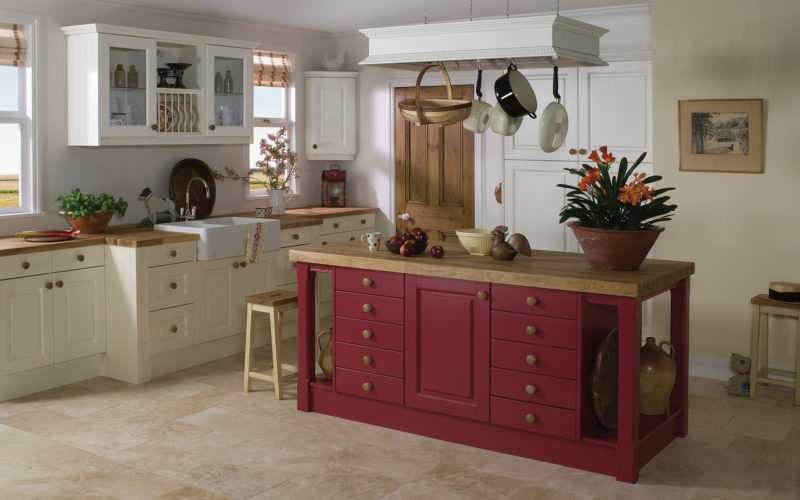 Traditional kitchen with a butler sink and cream cupboards. Showcasing a red kitchen island, all counter tops are wood.