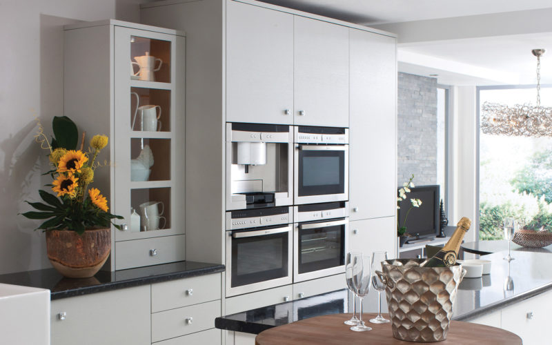Modern but classic white kitchen unit with built in coffee machine and ovens. Along with a matching display cabinet.
