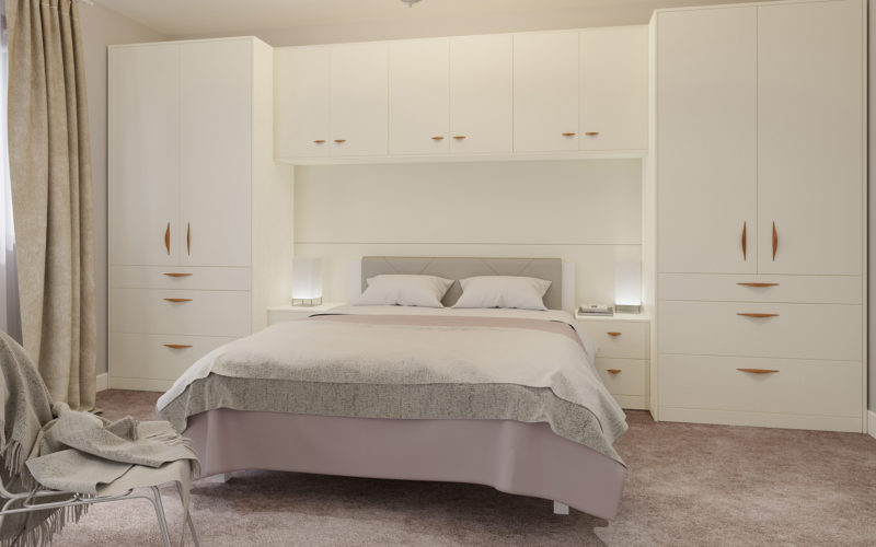 Modern light pink bedroom with modern white wardrobes which are built into the surround which goes around the bed. The surround also has two bed side tables.