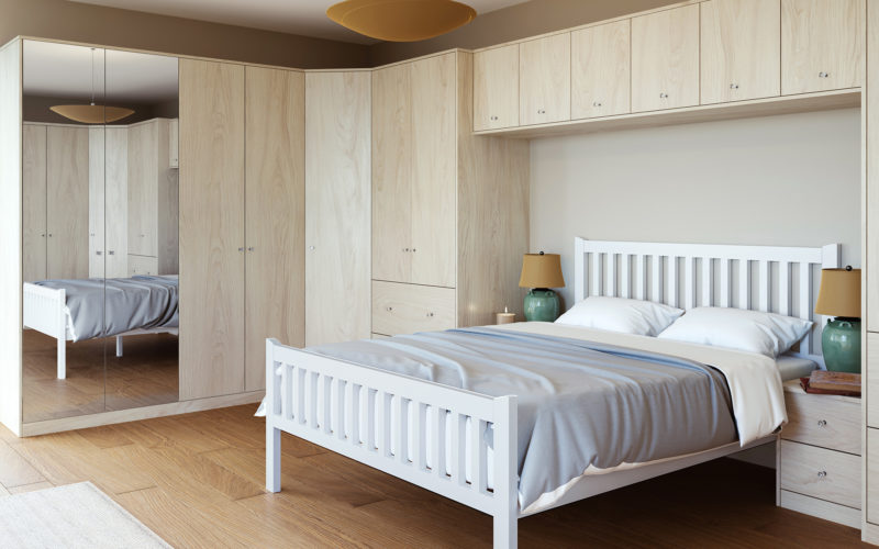 Bedroom with light wood bed surround which consists of cupboards and bed side tables.