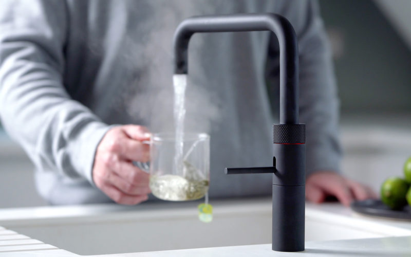 Quooker hot tap showing boiling water coming out of black tap straight into a mug of tea