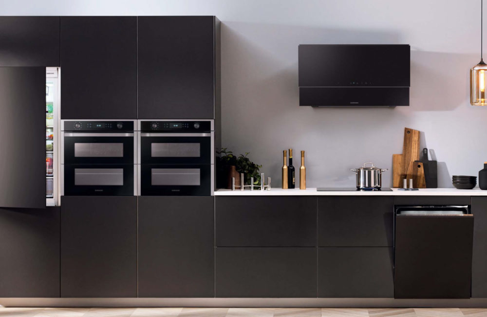 Black kitchen with Samsung appliances, which showcases a fridge, two ovens, a dishwasher, a hob and extractor fan.