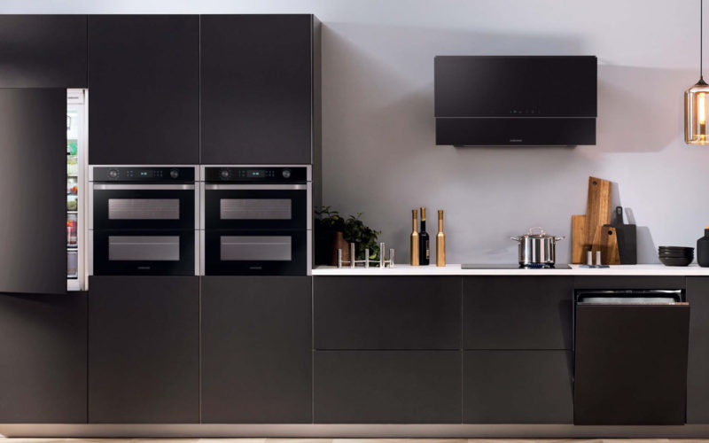 Black kitchen with Samsung appliances, which showcases a fridge, two ovens, a dishwasher, a hob and extractor fan.