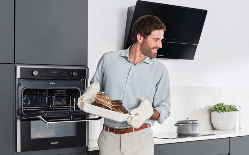 Man holding beef which has been cooked in his Samsung oven. This image also shows the Samsung extractor fan and a second mini oven.