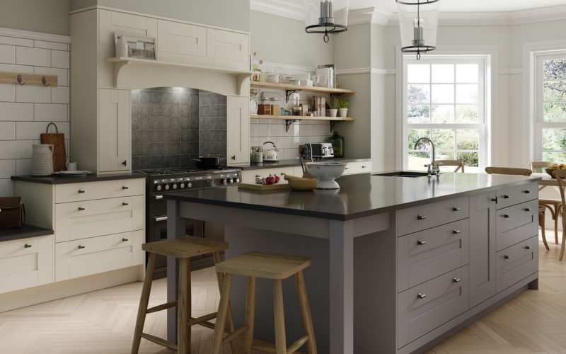 Large grey island with black countertop in an ivory cupboard kitchen