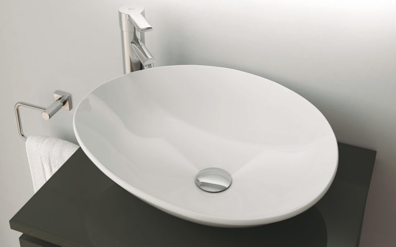 Modern white oval shaped sink on black counter top with a chrome tap