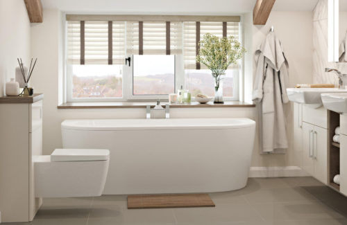 A beautiful white bathroom fitted in Ipswich, featuring a white bathtub, a styled shelf and bathroom ornaments.