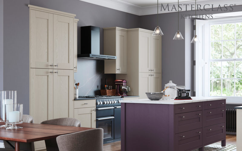 Shaker style cupboard and drawers in a cream colour. With an island that is in purple with a white counter top.