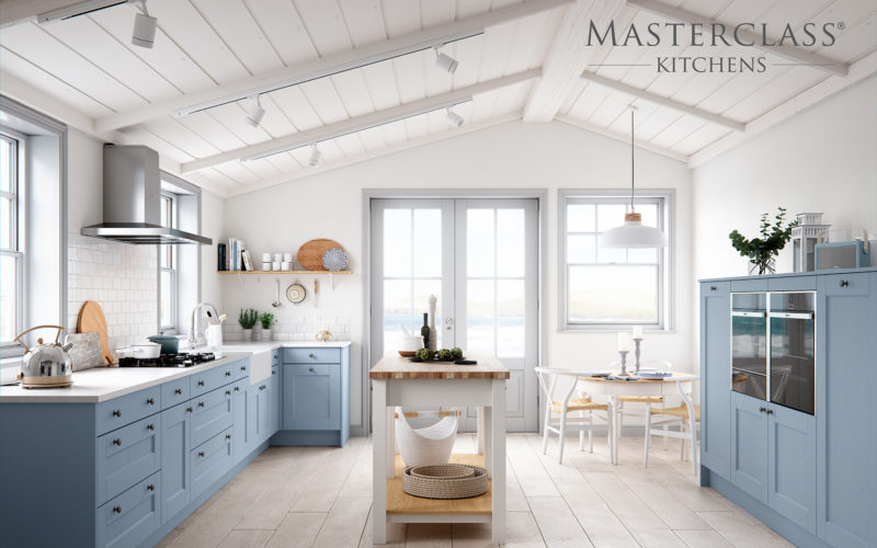 Seaside kitchen with blue coloured cabinets and a white kitchen island. The whole room is bright and white with matching blue cabinets on the other side of the room with built in ovens.