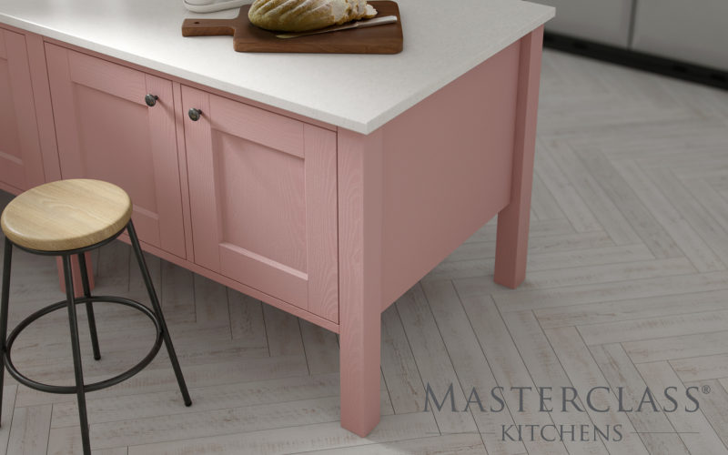 Close up image of a kitchen island in light pink with a white counter top